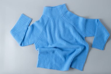 Yumuşak, ılık, mavi, lüks, doğal kaşmir süveterler, hafif, tarafsız arka planda yatıyor. Sonbahar ve kış saf yün giysiler. Örgü giyim modası..