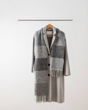 Beyaz arka planda metalik askıda asılı uzun tüylü alpaka eşarplı yumuşak gri bir yün ceket. Sonbahar ve kış saf yün giysiler. Modayı takip et..