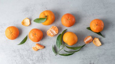 Sulu taze mandalina ya da mandalina ya da dilimli mandalina, yaprak ve kabuklu gri taş zemin. Doğal C vitamini kaynağı olarak turunçgil meyvesi.