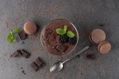 Naneli, böğürtlenli, çikolatalı ve siyah taş masa arkasında kurabiye bulunan cam kasede soğuk kakaolu süt tatlısı. Çikolatalı moka mus ya da retro kaşıklı dondurma..