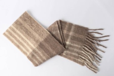 Alpaca yünü yumuşak sıcak atkıyı renk engelleyici tarzda karıştırır. Tarafsız arka planda katlanmış krem rengi kahverengi şal.