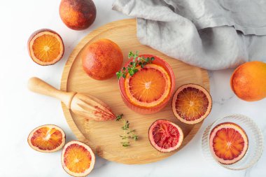 Kekik yaprakları, beyaz mermer arka planda, ahşap tepside, cam bir meyve diliminde serinletici soğuk portakal meyvesi. Tatlı limonata, kokteyl ya da taze taze kan portakalı suyu..