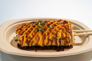 Lezzetli bir Okonomiyaki 'nin yakın plan görüntüsü Kağıt tabağa yapışmış.
