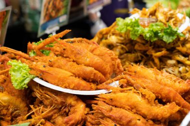 Beyaz bir tabakta taze yeşil marullu altın çıtır karides. Lezzetli deniz ürünleri ya da aperatif. Canlı renkleri ve dokusuyla yakın plan kızarmış yiyecekler..