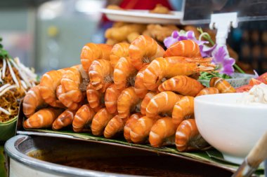 Deniz ürünleri pazarında tepside hazır parlak turuncu karides. Yakınlarda soslar ve süslemelerle satılmaya hazır taze deniz ürünleri. Pazar gıda gösterimine yakın çekim.