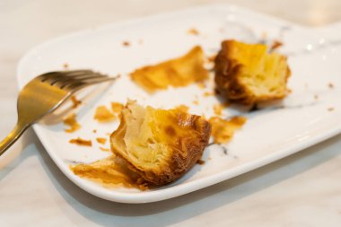 Masasında çatal olan beyaz bir tabakta bitirilmemiş bir çöreğin yakın çekimi. Görüntü, modern ve minimalist bir kafe ortamında keyif, hoşgörü ve rahatlamayı çağrıştırıyor..