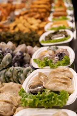 Açık büfede taze sebze ve sosla servis edilen çeşitli hamur tatlısı ve mezeler.