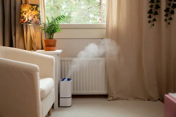 Modern air humidifier in action in living room. Contemporary smart humidifier in bedroom emitting water vapor and moisturizing air in cozy room