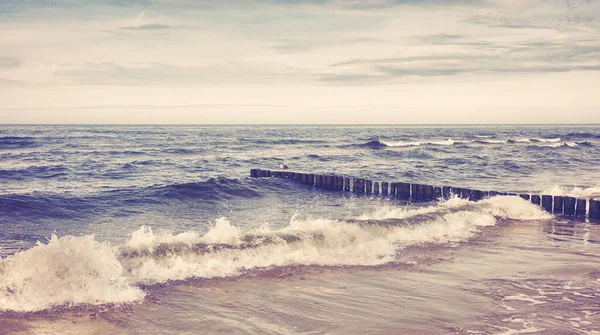 波が砕ける空のビーチのレトロなトーンの写真 — ストック写真