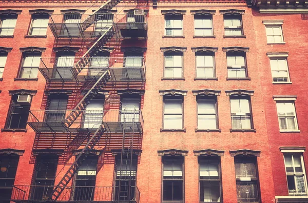 Old townhouse building with iron fire escape, color toning applied, New York City, USA.