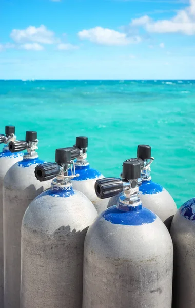 Close up picture of scuba tanks with turquoise water in the background, selective focus.