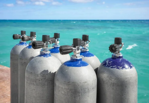 Close up picture of scuba tanks with turquoise water in the background, selective focus.