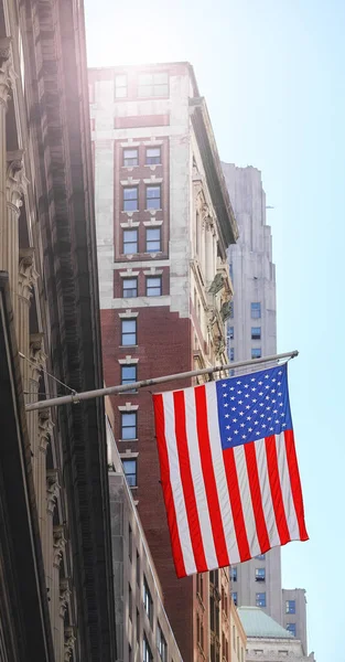 American flag with buildings in background, selective focus, New York City, USA.