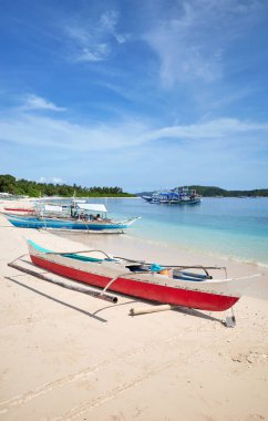 Bangka fishing boats on the beach of Inapupan Island in the Philippines. clipart