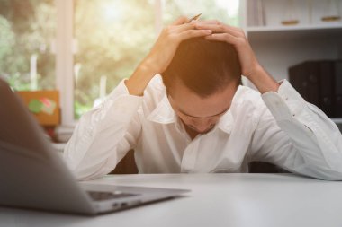 Asyalı iş adamı yorgun bir şekilde masada yatıyor.