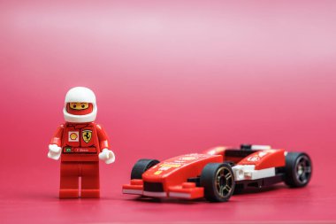 Bangkok, Tayland - 28 Eylül 2022: Kırmızı arka planda Ferrari yarış arabasının Lego minyatür sürücüsü.
