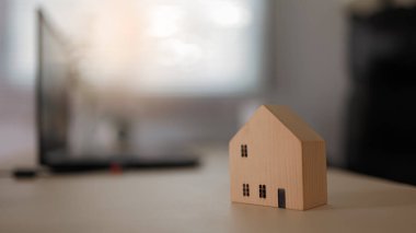 Ev modeli ahşap masada emlak konseptini gösteriyor.