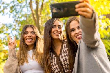 Parkta gülen kadın arkadaşlarının selfie 'si kaygısız, modaya uygun sonbahar yaşam tarzı.