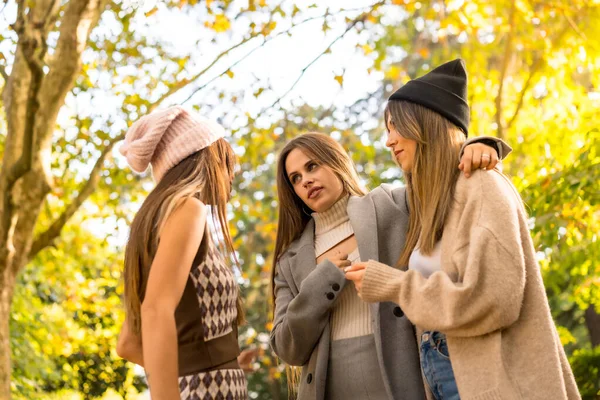 Women friends talking in a park in autumn at sunset, Lifestyle and autumnal outfit