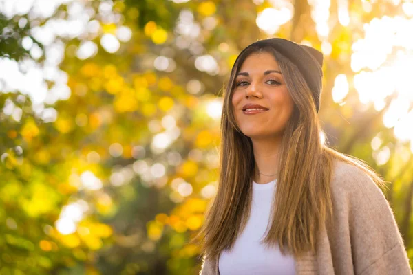 Stock image Portrait of a young blonde girl in a woolen hat in autumn, walking in the park at sunset