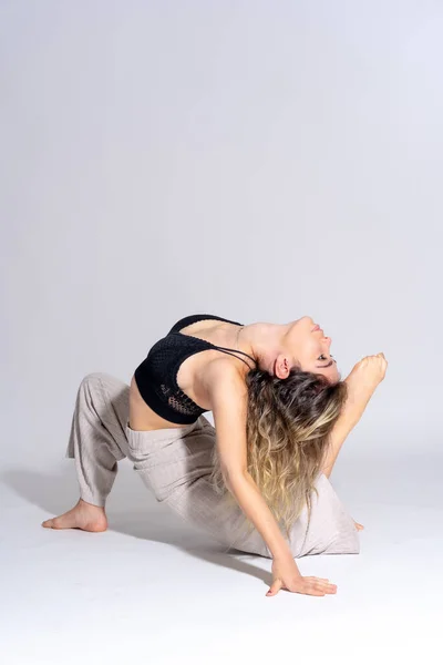 stock image Young dancer in a studio photo session with a white background, ballerina, ballet, performing exercises on the floor