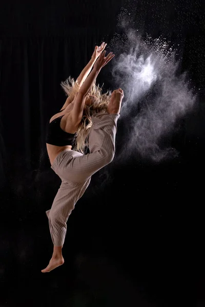 Young dancer performing a jump in studio photo session with a black background, ballet