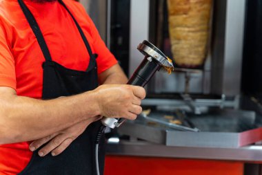 Kebap lokantasının şefi, ızgaradaki eti kesmek için elektrikli aleti kullanıyor.