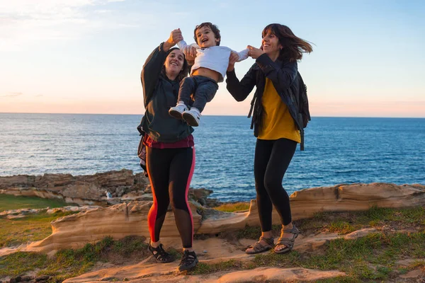 stock image Aunt of the child and mother playing with him child on the coast by the sea at sunset