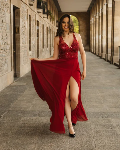 Caucasian woman in a red gala dress, model walking towards the camera