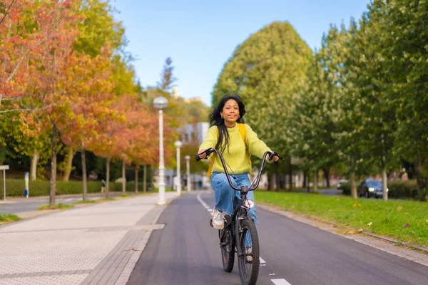 Young Asian female student riding a bicycle on her way to university along the bike lane, healthy living, eco-friendly