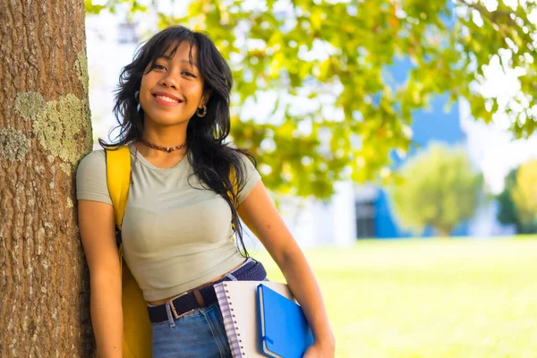 キャンパスのアジアの女の子は 手とバックパックでブロックと木の下の大学で笑顔 — ストック写真
