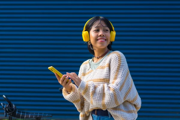파란색 배경으로 노란색 헤드폰을 음악을 아시아 소녀의 — 스톡 사진