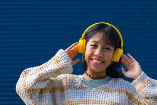 Ασιάτισσα Νεαρή Γυναίκα Διασκεδάζει Ακούγοντας Μουσική Κίτρινα Ακουστικά Μπλε Πανεπιστημιακό — Φωτογραφία Αρχείου