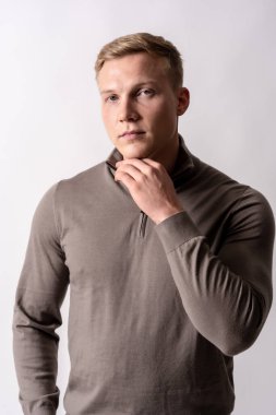 Beyaz arka planda kahverengi kazaklı sarışın beyaz bir adamın portresi.