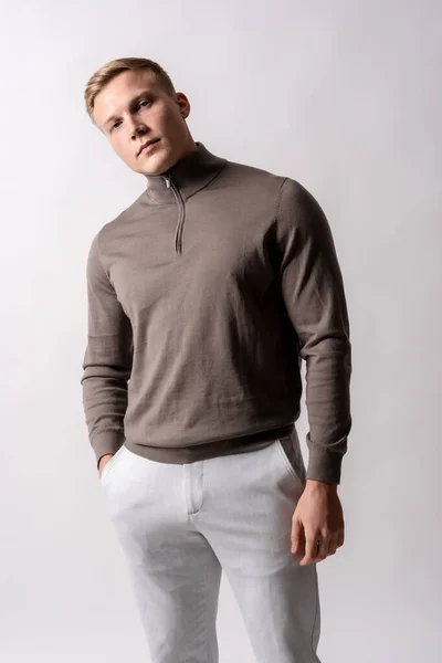 stock image Portrait of an attractive blond german model with a brown sweater on a white background, looking at the camera