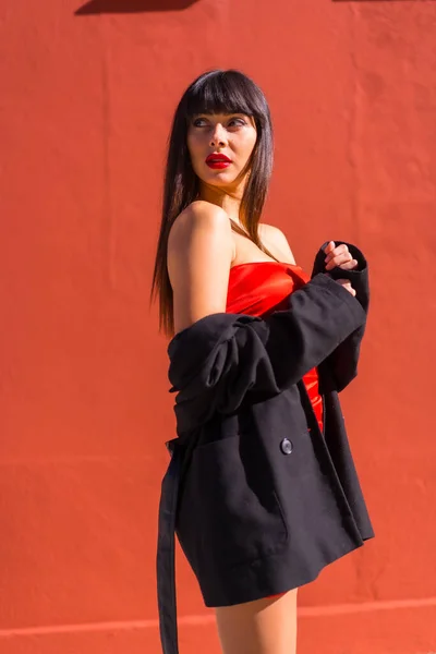 ブルネットモデルは 赤い背景 赤いドレス 挑発的な女の子の肖像画にポーズ — ストック写真