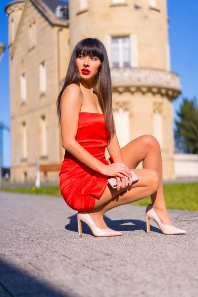 穿着红色衣服的年轻女人 蹲在漂亮的城堡里 摆出时尚的姿势 面带微笑 — 图库照片