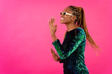 Pembe arka planda parti örgüleri olan Afrikalı genç bir kadın. Stüdyo dansı.