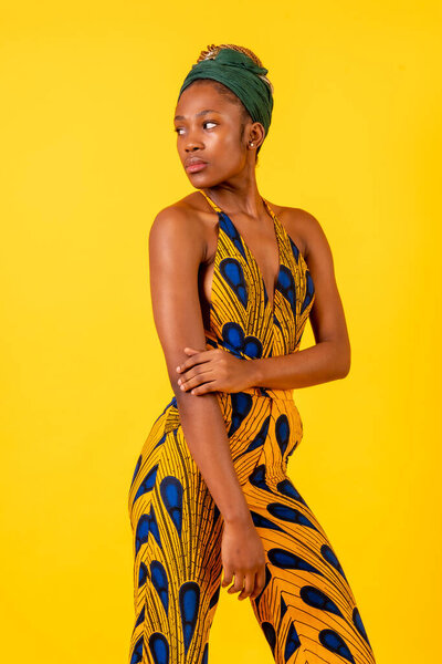 African young woman in the studio on a yellow background, portrait in a traditional costume looking
