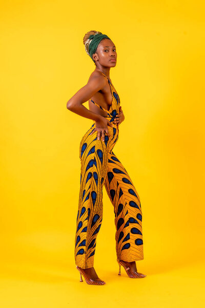 African young woman in the studio on a yellow background, traditional costume