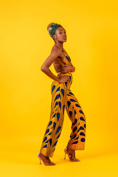 African young woman in the studio on a yellow background, traditional costume