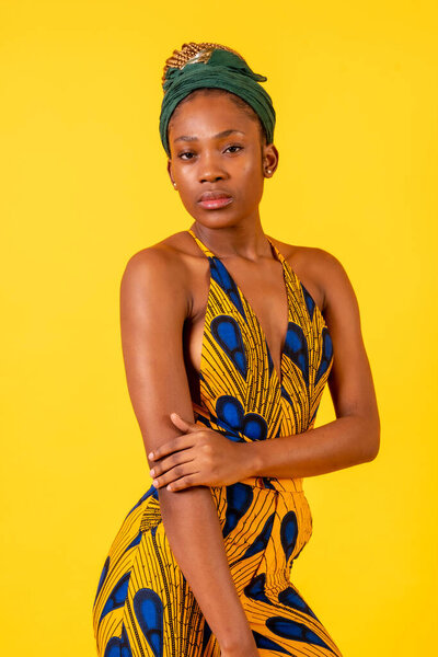 African young woman in the studio on a yellow background, portrait in a traditional costume looking at the camera
