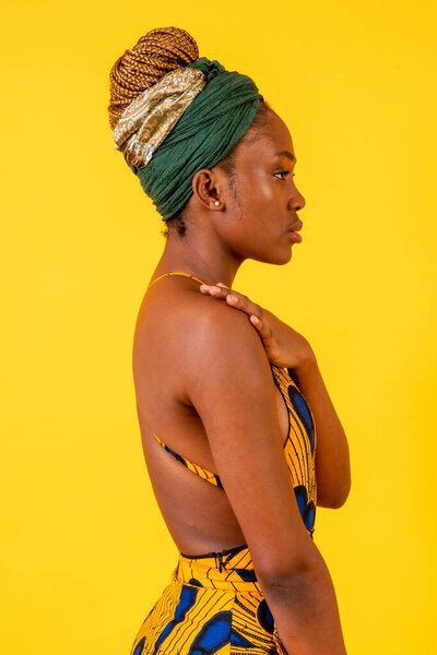 African young woman in the studio on a yellow background, traditional costume, vertical photo