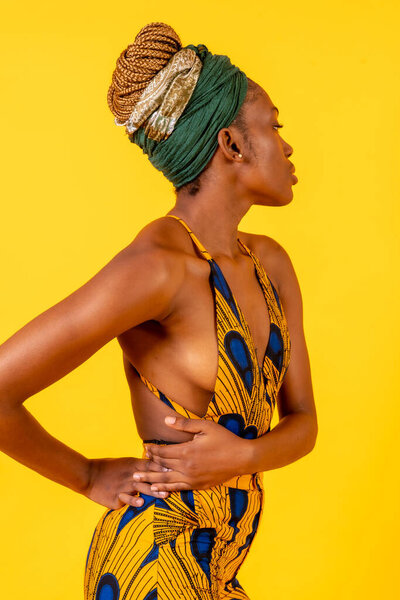 African young woman in the studio on a yellow background, traditional costume, looking to the right