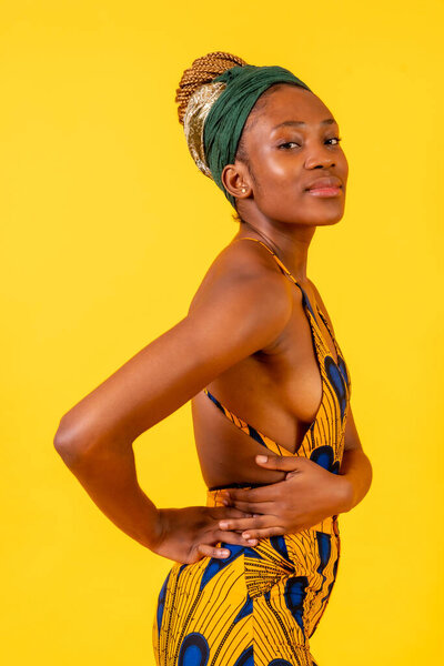 African young woman in the studio on a yellow background, traditional costume, smiling