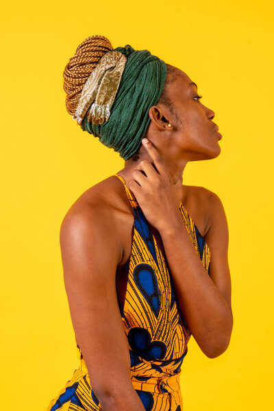 A person woman of black ethnicity with traditional costume on yellow background, profile model