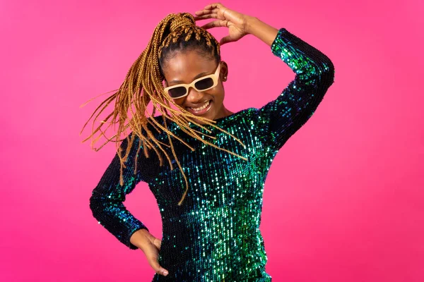 African young woman with party braids on a pink background, smiling having fun dancing