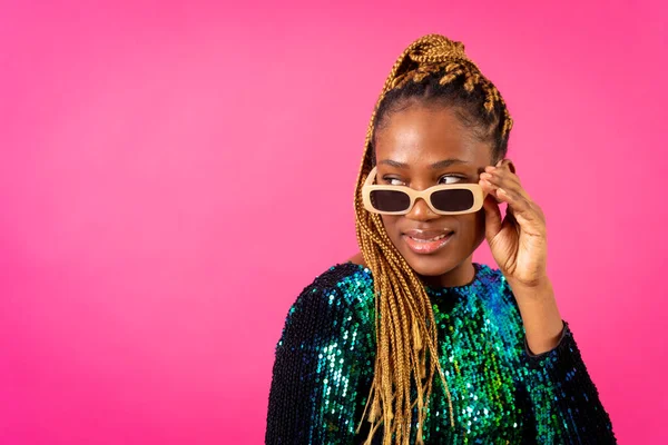 African young woman with party braids on a pink background, studio portrait with glasses