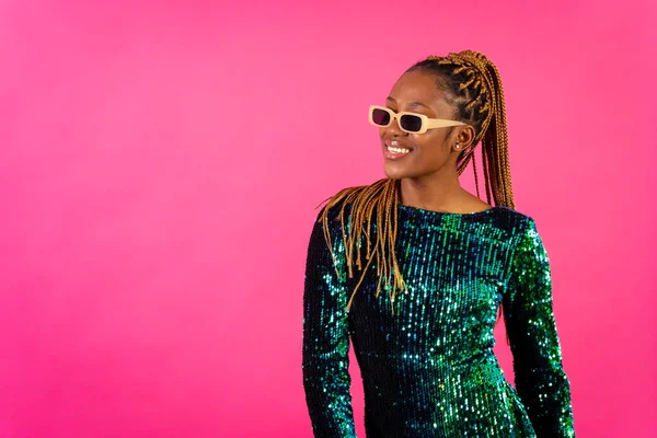 African young woman with party braids on a pink background, studio portrait having fun