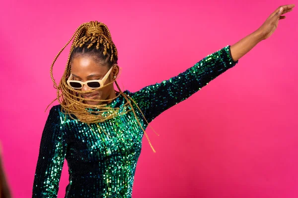 African young woman with party braids on a pink background, studio portrait in sunglasses